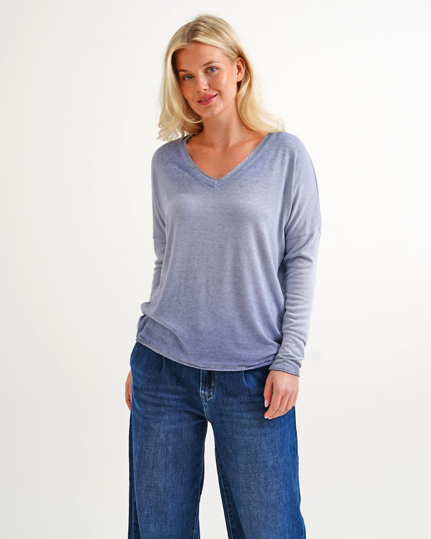 Woman wearing a blue long-sleeve top and jeans on a white background