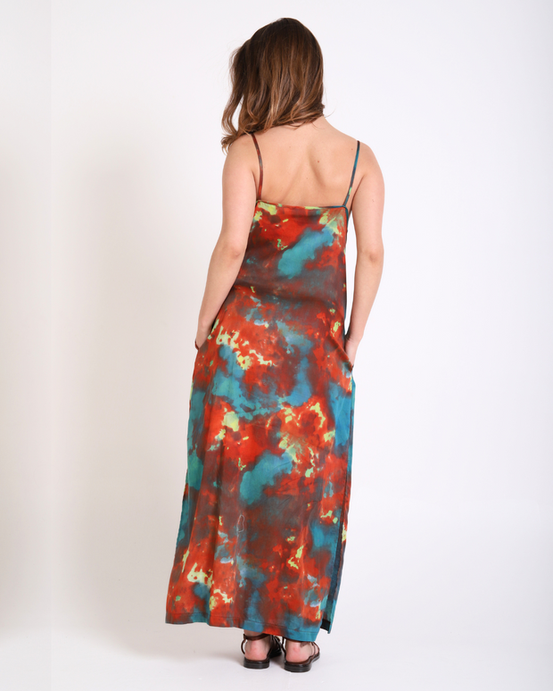 Woman wearing a tie-dye dress with red, blue, and green patterns on a white background
